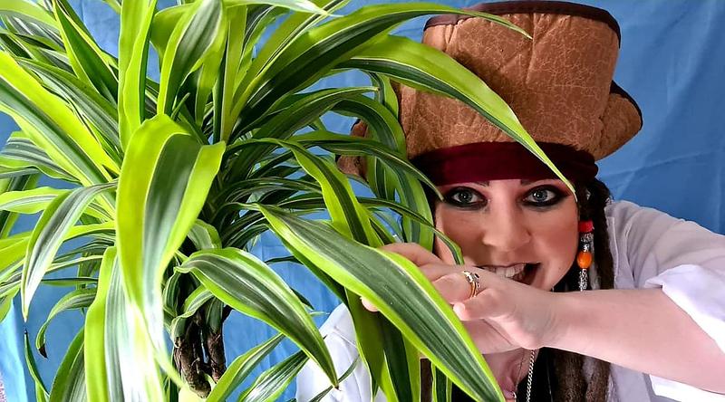 Heather K Taylor standing in pirate costume behind a plant